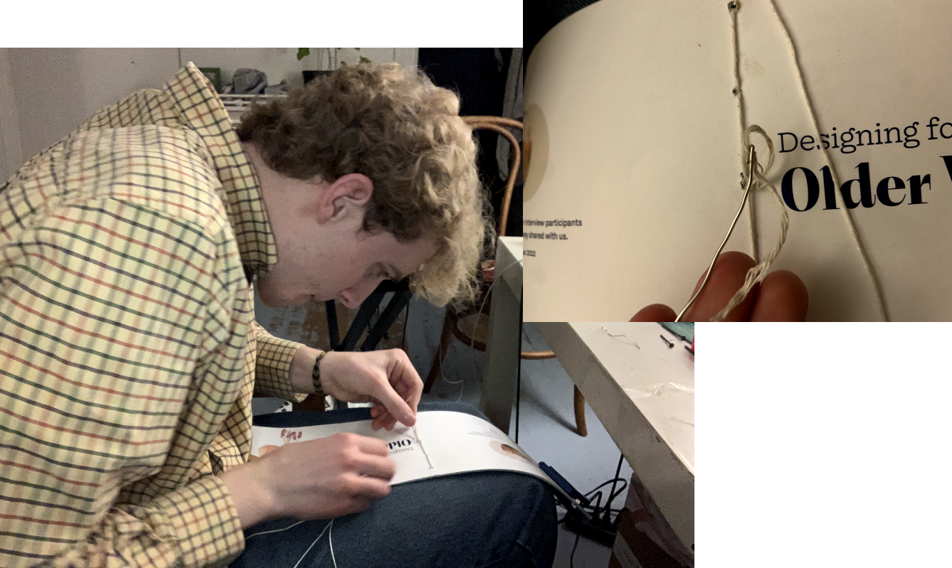 A photo of me in the process of using a makeshift sewing needle to saddle-stitch the sheets together for the workbook
