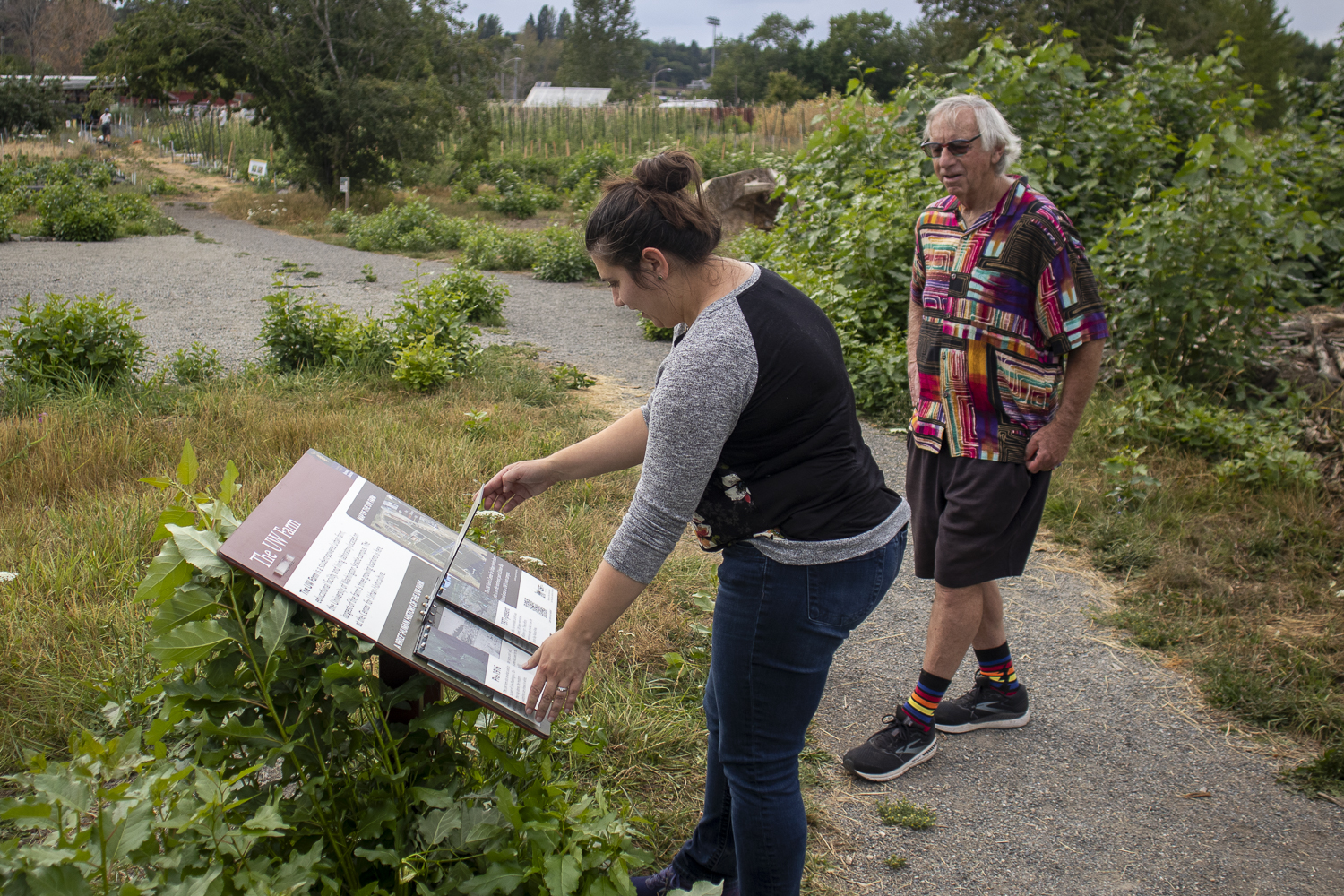 Visitors lift the flap of the sign at the east entrance of the farm